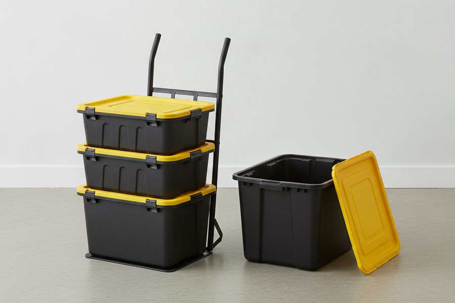 Illustration of three black boxes with yellow lids stacked on a hand truck dolly, with one open, empty box beside them